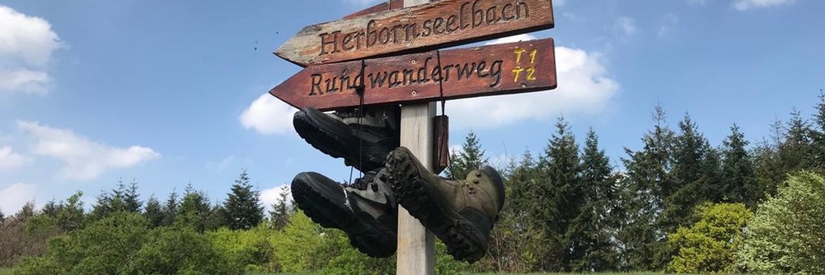 Richtungsschild Rundwanderweg Hohe Straße mit Wanderschuhen